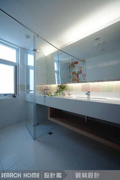 同樣是一字型衛浴空間，利用石材從台面延伸到浴缸，線