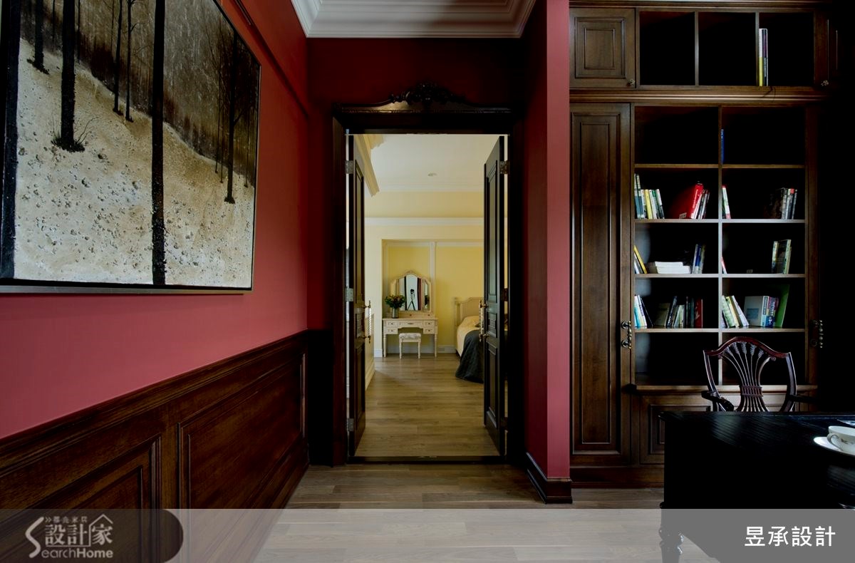 加大書房進出主臥空間的門片設計，以深色的柚木貼皮雙開門扇搭配著古典造形門斗，映襯著大膽採用紅色刷漆的書房空間，一深一淺、一明一暗，為空間畫下光與色彩的動人翦影。