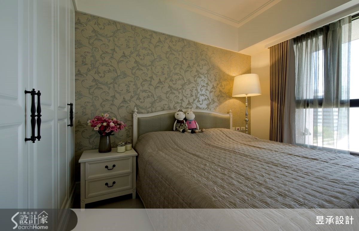 主臥室床頭選用古典圖騰紋飾的壁紙，搭配同色系窗簾，承襲與公共空間一致優雅美式風格。