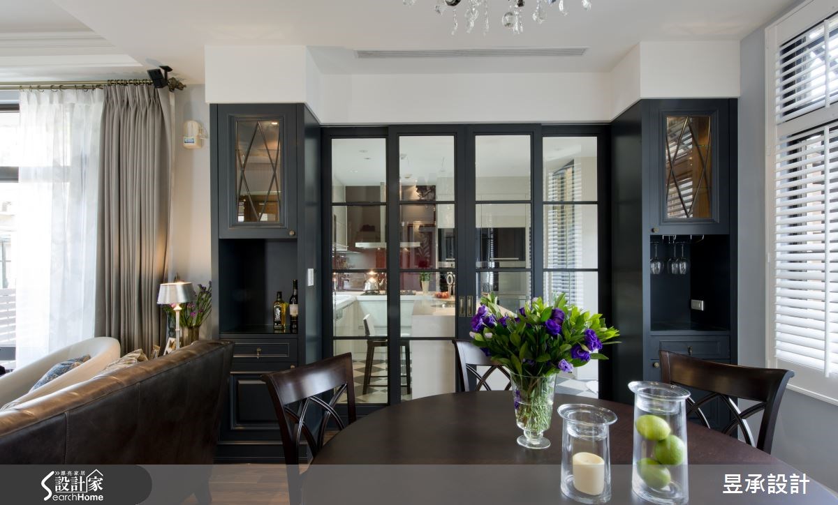 餐廳與廚房之間，設置對稱且中間特意鏤空的收納高櫃，既可以完全隱藏與廚房區隔的木格玻璃門扇，閉合時更展現出餐廳空間的色彩與視覺層次。