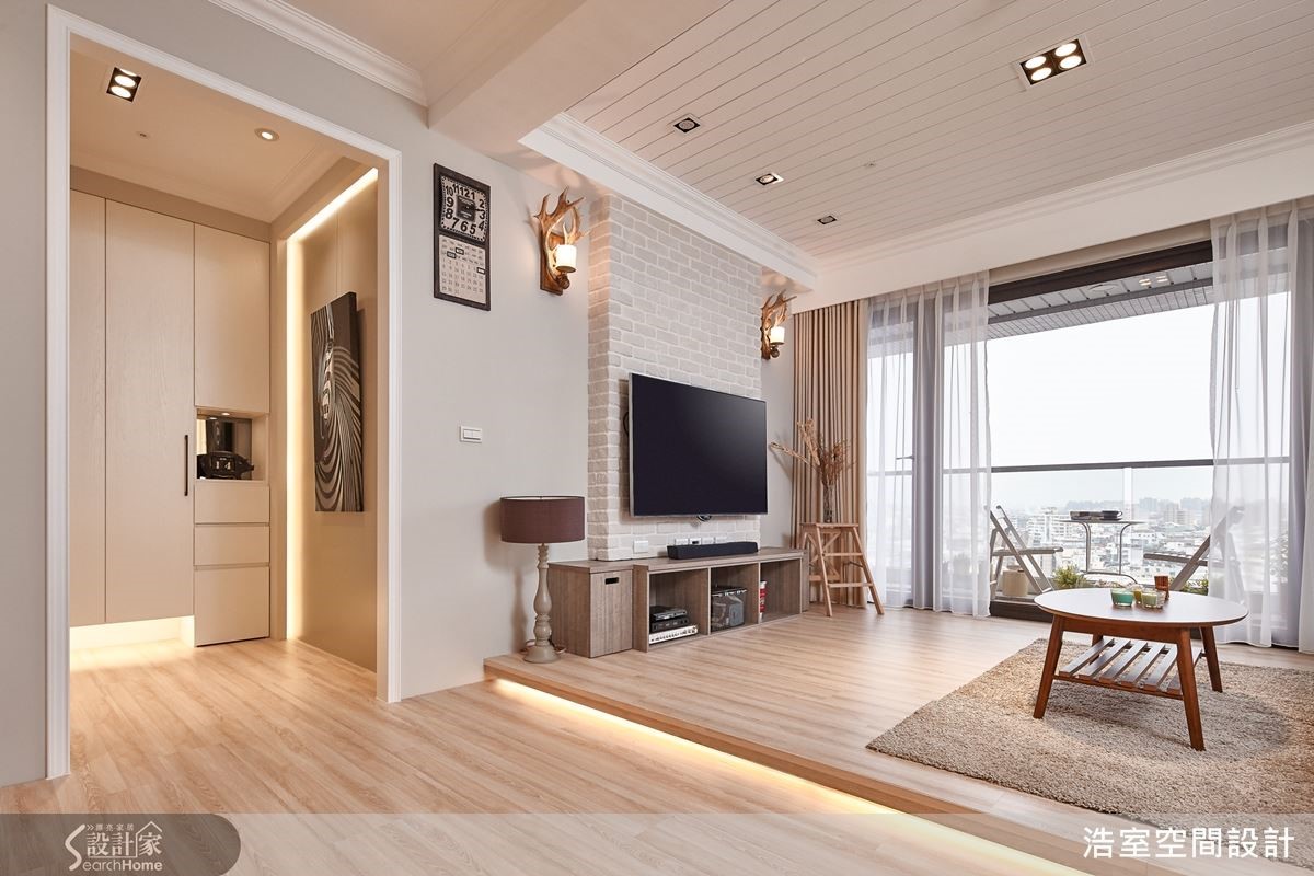 客厅刻意採取架高木地板的设计来界定区域，下方加设的灯光更让空间有种难以言喻的细腻温暖。