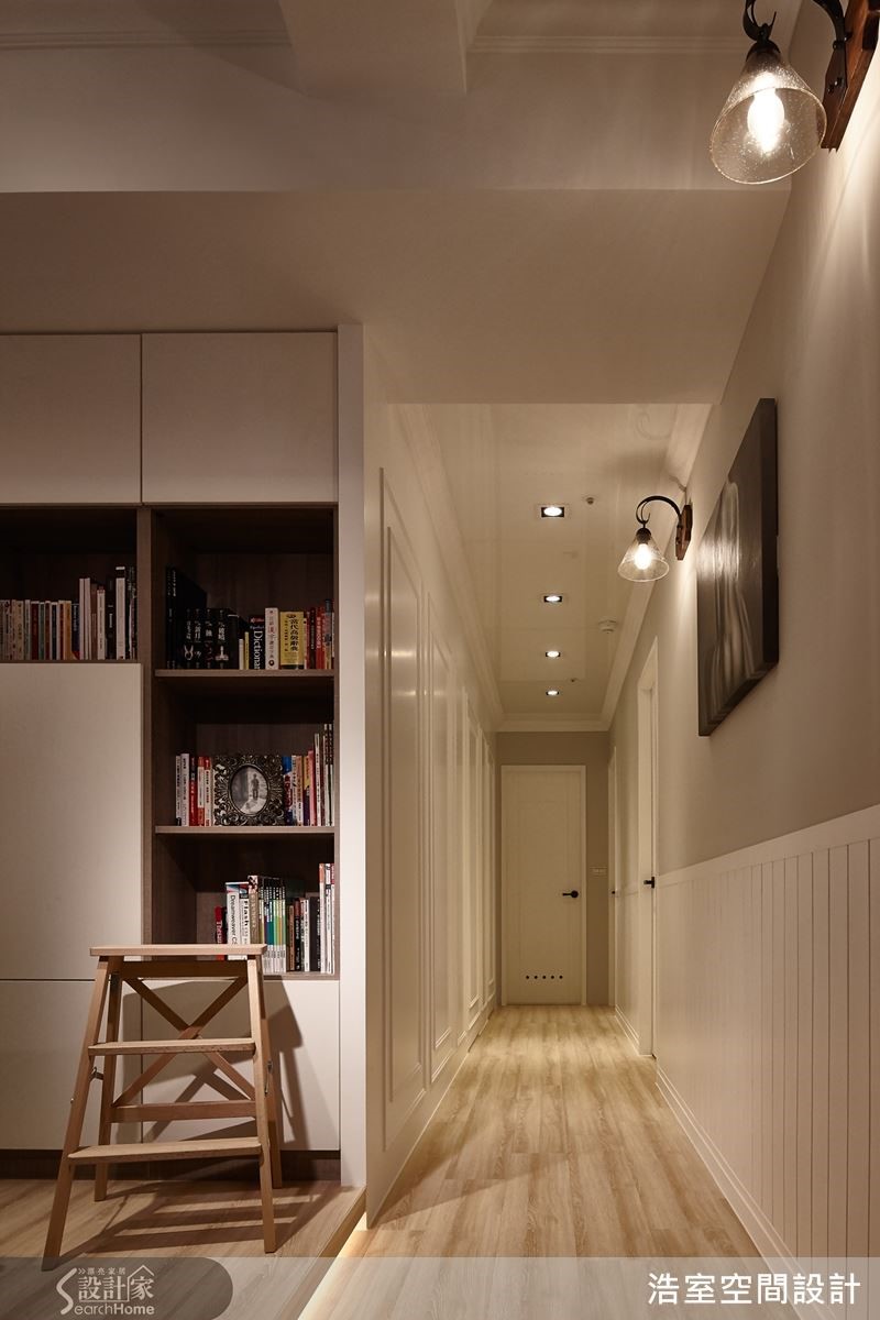 走廊左侧墙面以线板修饰并隐藏卧室门，右侧墙则以壁灯打亮层次感，让走廊不会显得狭隘。