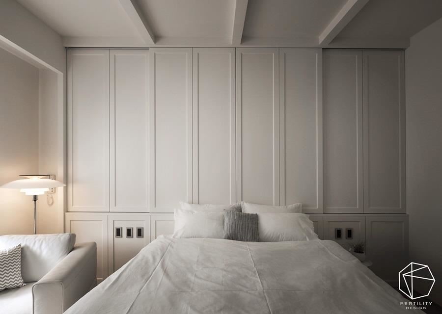 床头正位于梁下，因此设计师规划出有高低差的斜屋顶，并在背墙设置一整片的收纳柜，既有线条装饰感又极具功能性。