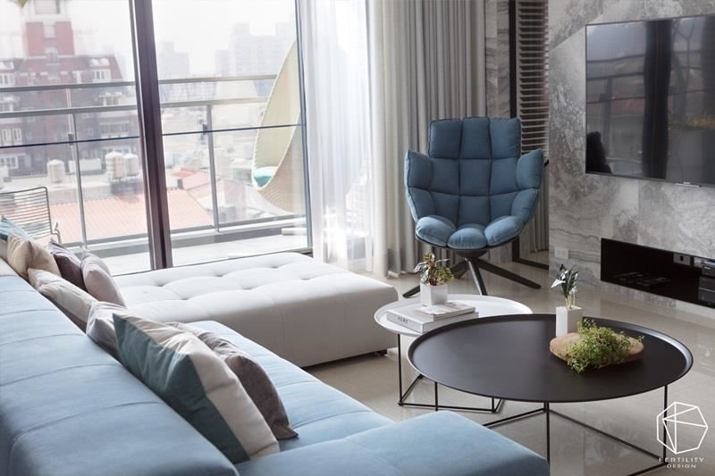 客厅陈列 L 型沙发、单椅等家具，透过各种深浅不一的蓝色调交织，营造美好层次。