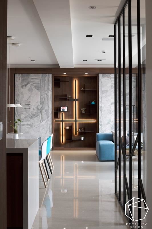 客厅背墙亦是走道端景，设计师特意在两面纹理丰厚的大理石墙面中，留出一面开放性展示柜，内嵌十字架造形灯，由着地面反射出的光束，活化了整体氛围的流动，成为一大视觉焦点。