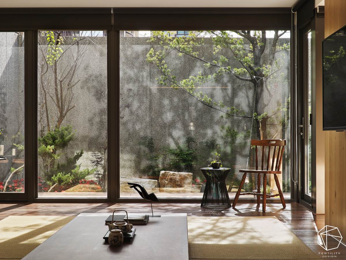 落地窗外布满美好绿栽，伴随着日光变化，筛落成千变万化的树影姿态，构成室内最天然的妆点元素，并摆置桌几与单椅，形塑充满日式风情的檐廊，可静待四季、坐看云起，尽情饱览庭院风景。