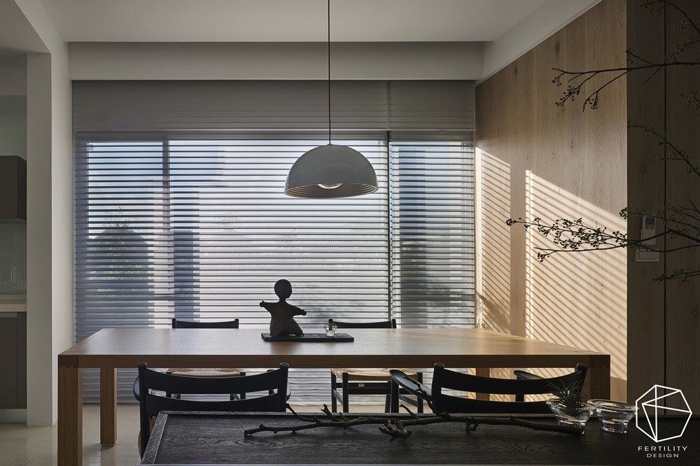 楼梯旁侧的闲置空间作为餐厨场域，采以开放式规划，藉由窗景迎接露台的绿意美景，同时安装卷帘引导光线，任光影筛落木皮墙面，围塑自然休闲的氛围。