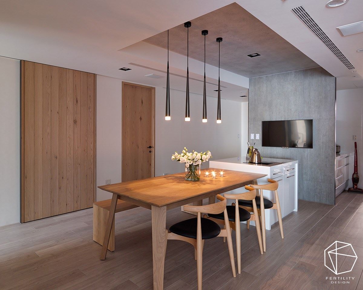 仿清水模的建材延伸至餐厅天花板，搭配木桌和木椅，形塑充满疗愈感的餐厨空间，让人倍感温馨，再加上一组电视，让人能一边享受食物，同时观赏节目或电影。