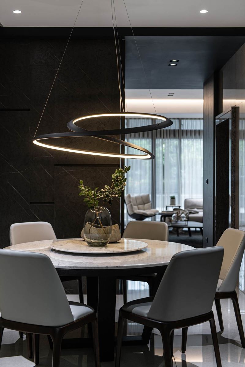 在餐厅天花板悬挂进口餐吊灯，提升餐区的质感氛围，并选用意大利设计品牌的餐吊灯，背后则透过灰黑色仿石纹系统板铺叙壁面，成功包覆卫浴门片，让人忽略入口存在，提升餐厅的质感。