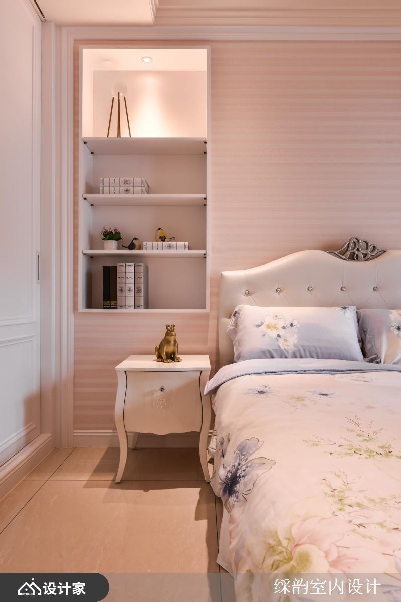 粉色调为主的居室里，床头背墙嵌入开放柜体，陈列书籍与风格小物，下方搭佐一张雅致的古典矮柜，创造柔美的动人端景。